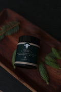 Jar of Verity Wellness whipped organic tallow body butter on a textured surface with green leaves.